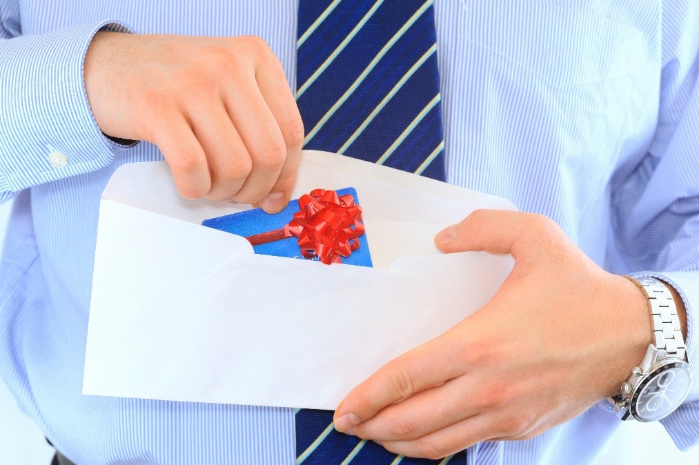 Man holding an envelope and putting a gift card inside.