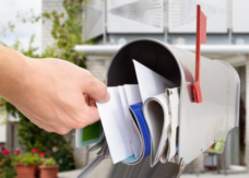 Close Up of a Hand Pulling a Large Bundle of Mail Out of a Silver Mailbox